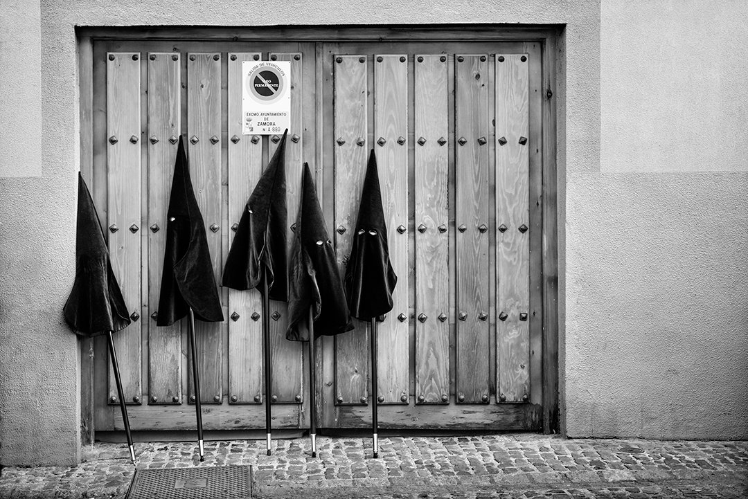 Capirotes colgados en una puerta de madera.